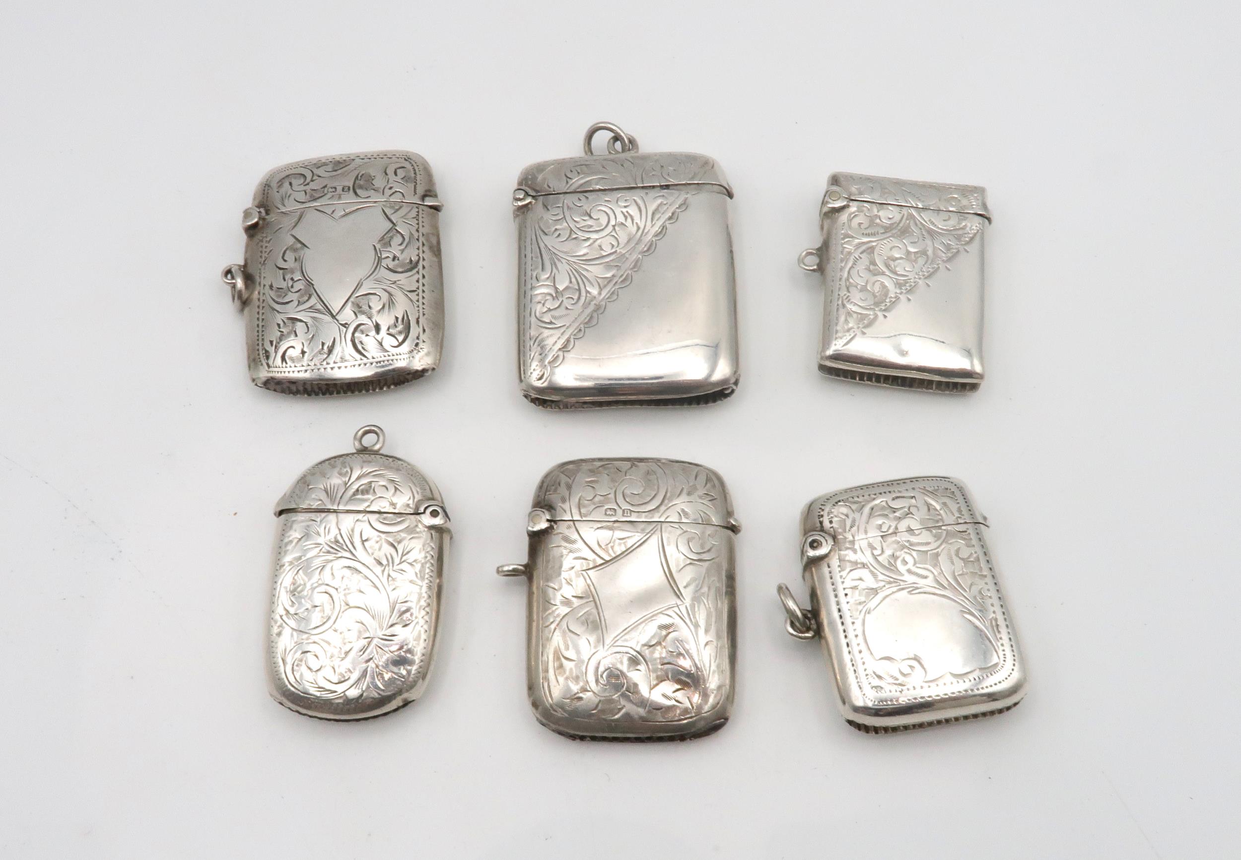 A collection of silver vestas, all with engraved scrolling foliate decoration, five with vacant