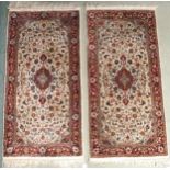 A lot of two cream ground rugs with red central medallions on floral pattern grounds with dark red