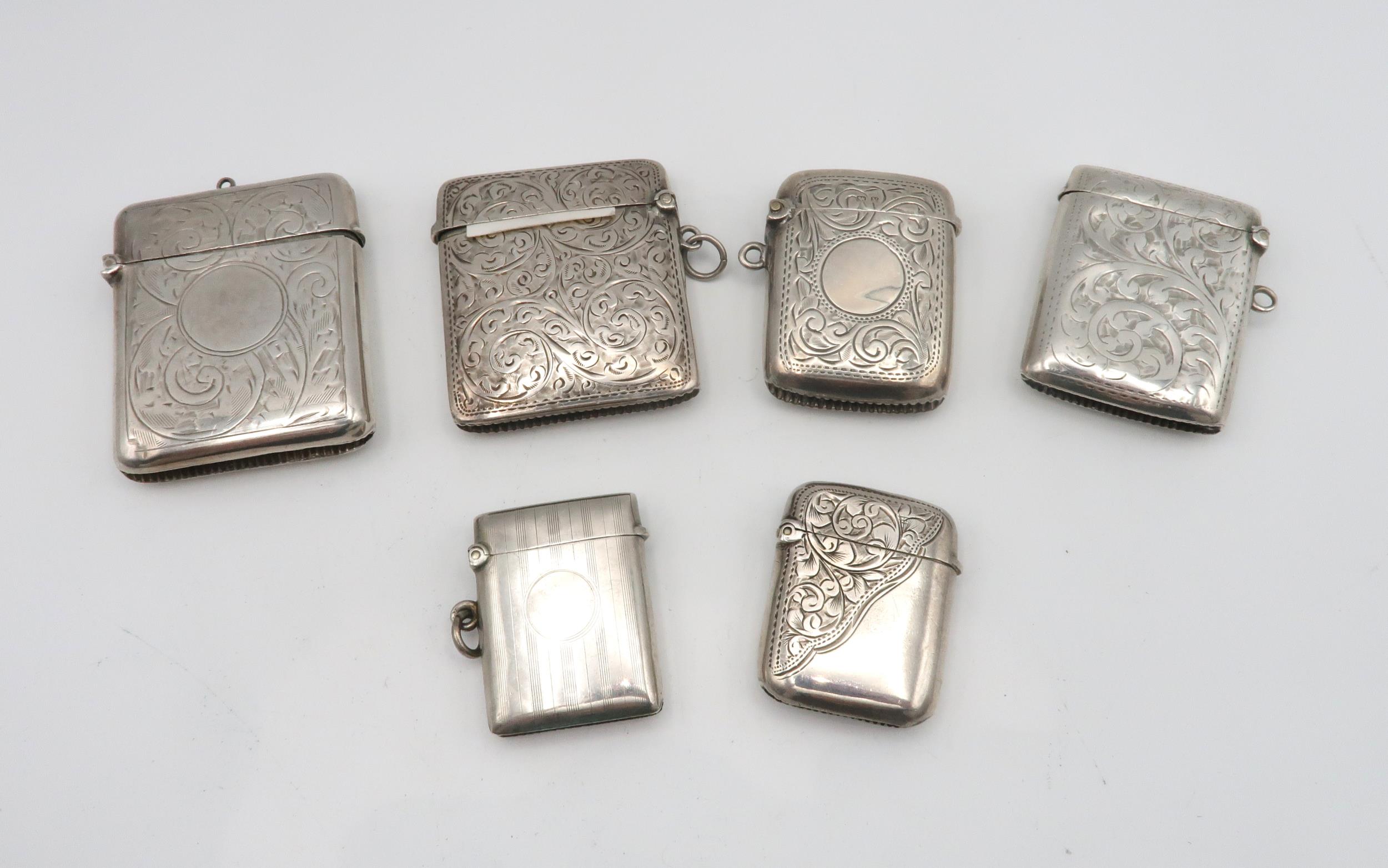 A collection of silver vestas including an example with scrolling foliate decoration surrounding a
