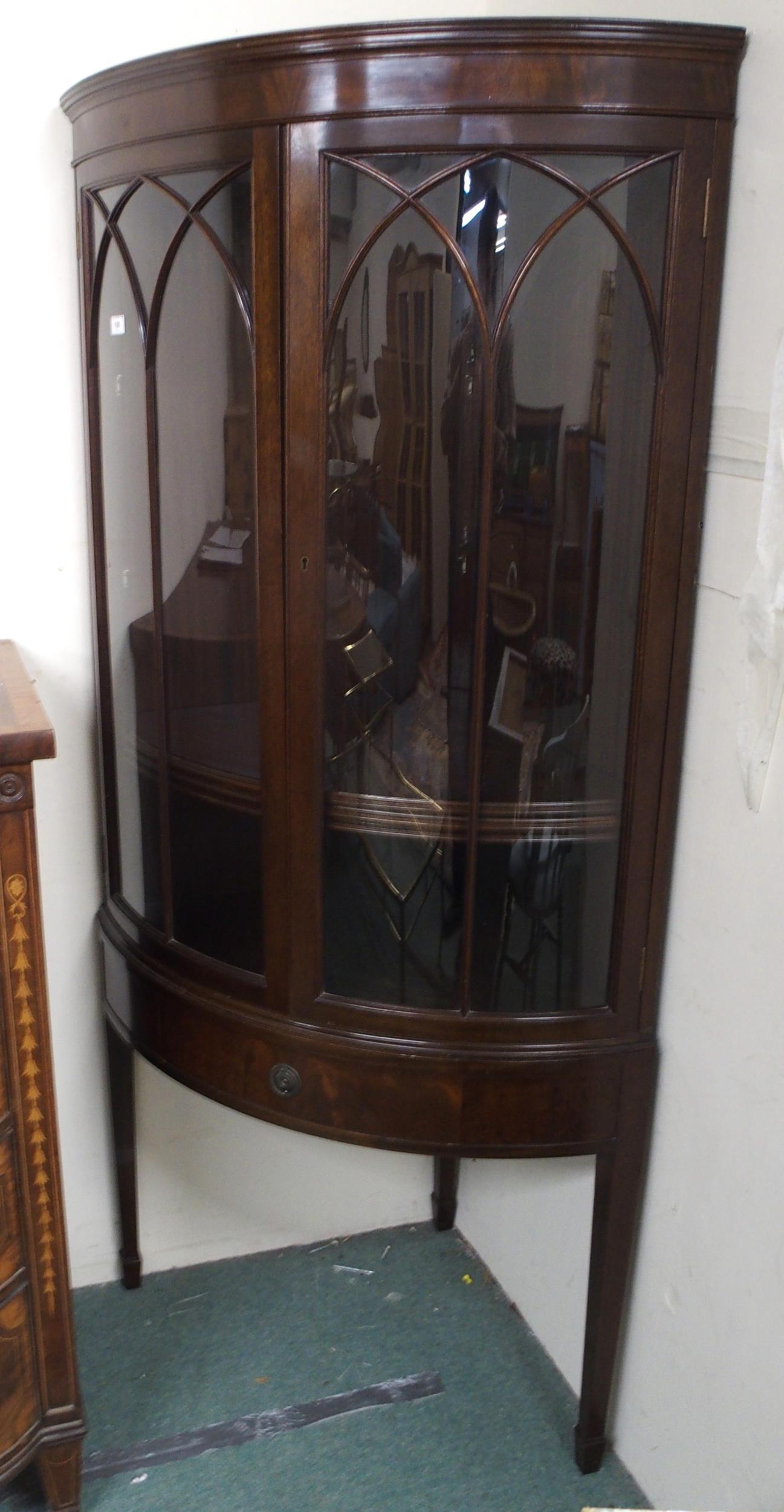 A 20th century mahogany bow front glazed corner cabinet with pair of glazed doors over single drawer