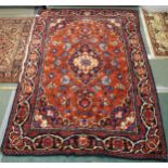 A terracotta ground Kashan style deep pile rug with dark blue central medallion and matching