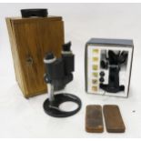 Two binocular microscopes, one cased, one boxed, together with a pair of leather-covered map weights