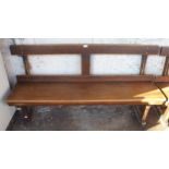 An early 20th century beech bench/pew with plain back on chamfered square supports, 79cm high x