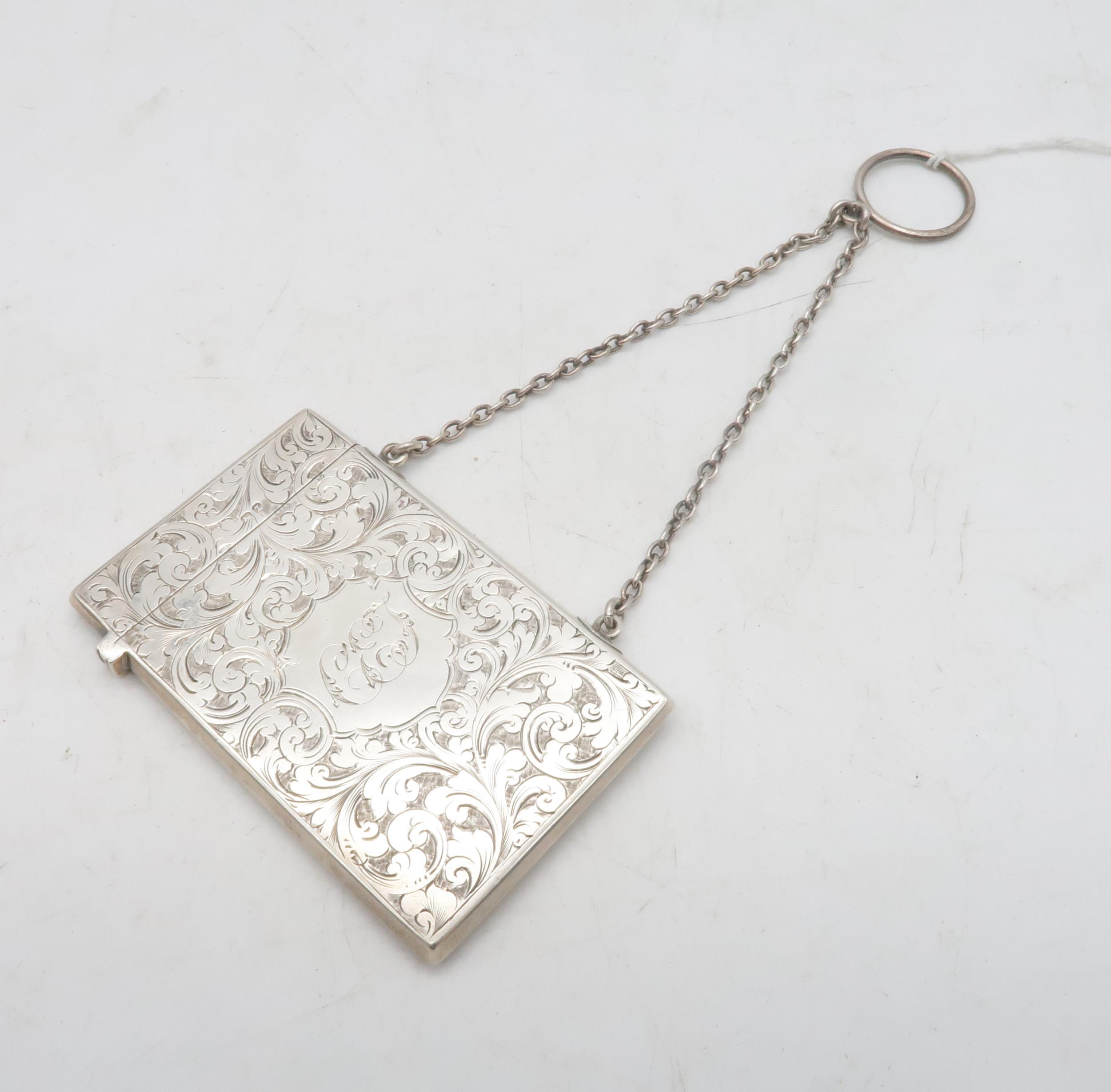 A late Victorian silver card case, the body engraved with scrolling foliate decoration surrounding a