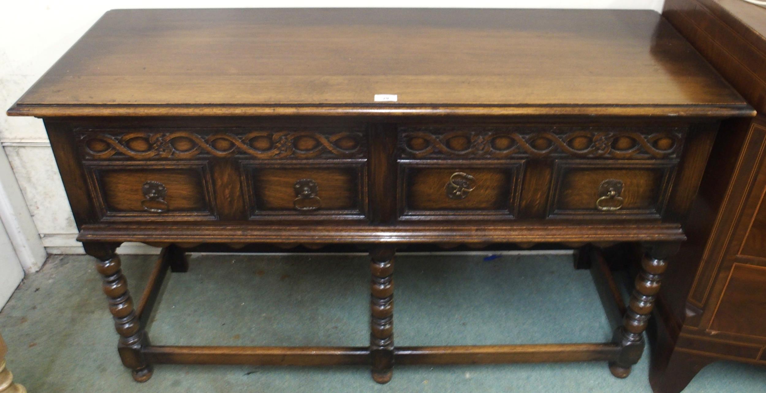 A 20th century oak baronial style two drawer buffet table on stretchered bobbin turned supports,