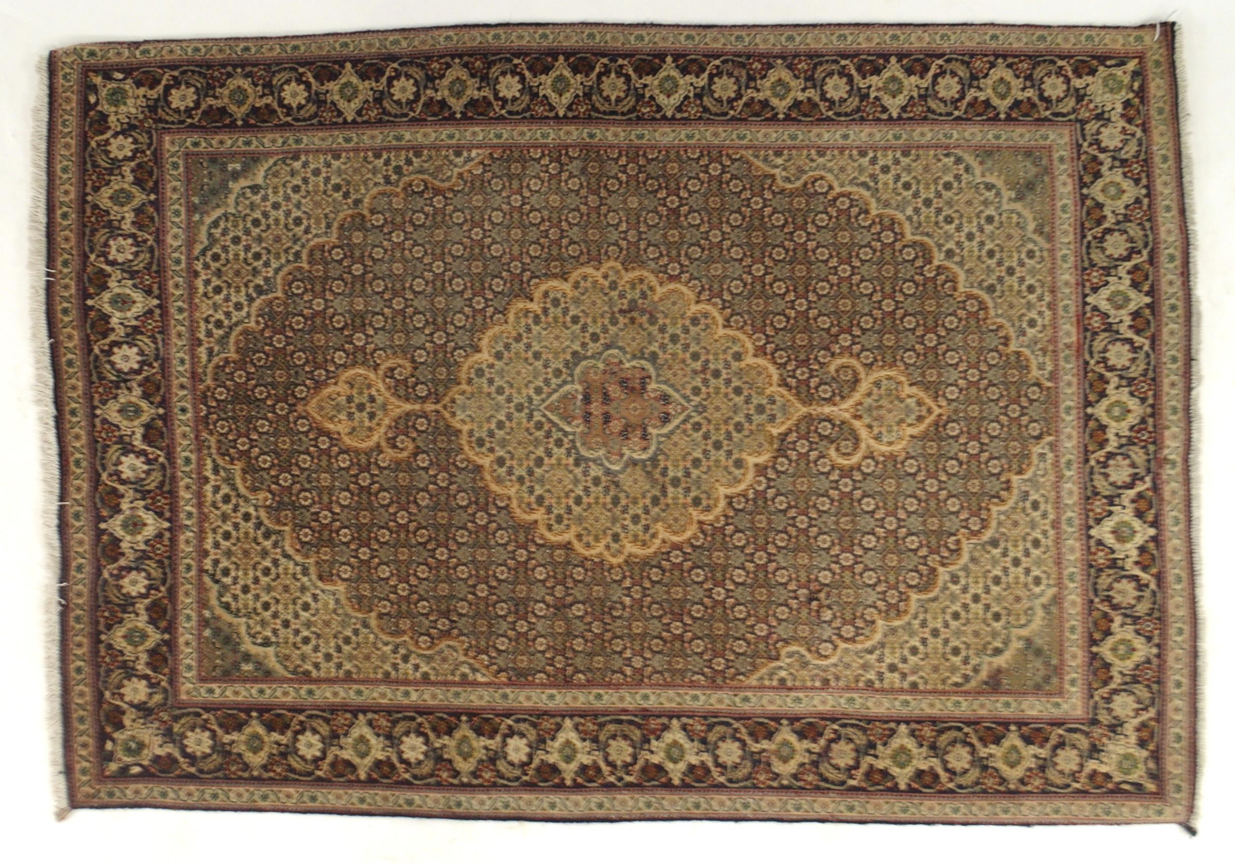 A multicoloured ground Tabriz rug with green central medallion, matching spandrels and a dark blue