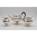 A three piece silver tea service, of lobed form, on footed lobed bases, with scrolling handles, by