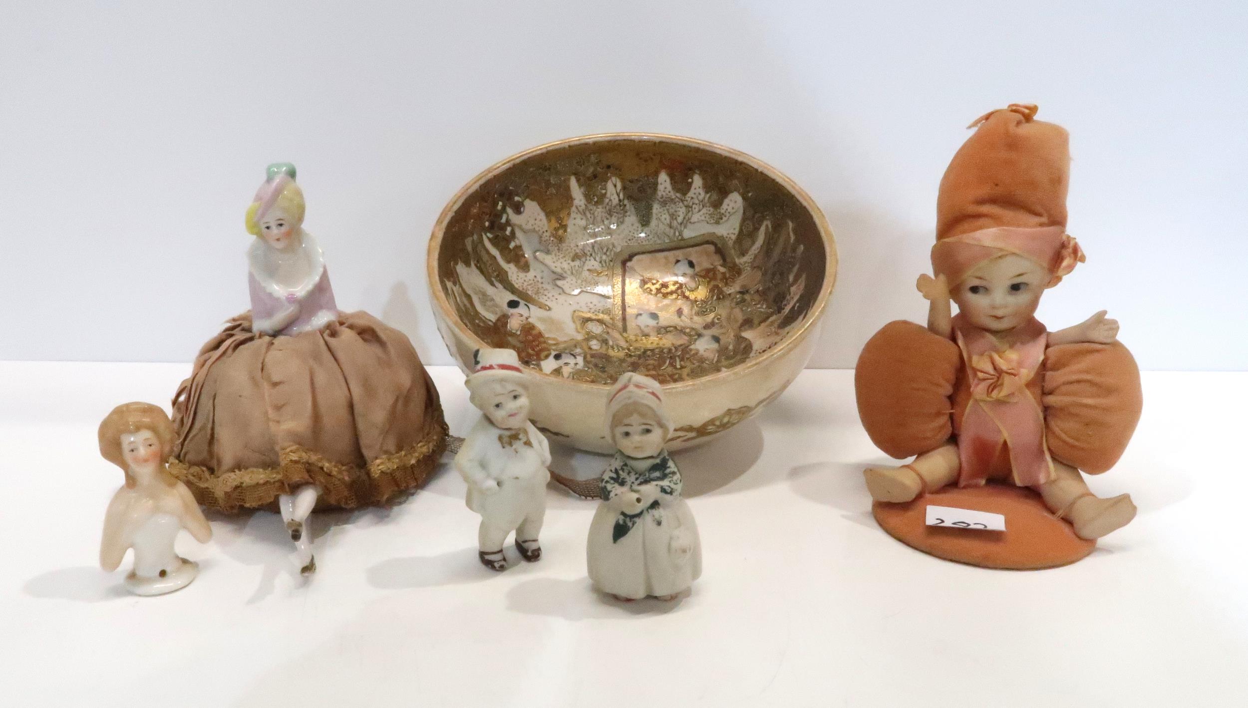 A Satsuma bowl decorated with figures, a porcelain baby pin cushion, half doll pin cushion,