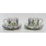 A pair of 19th century Meissen flower encrusted cups and saucers, each with additional painted