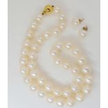 A string of uniform cultured pearls, approx. 1cm diameter, with slight pink lustre, 21cm long,