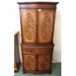 A 20th century mahogany reproduction bowfront cocktail cabinet with pair of doors concealing