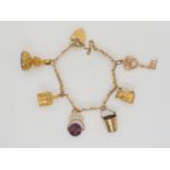 A 9ct gold charm bracelet with heart shaped clasp, hung with six 9ct hallmarked charms to include