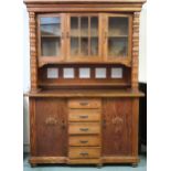 A 20th century pine glazed kitchen dresser with three glazed cabinet doors flanked by carved columns