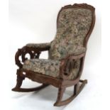 A Victorian walnut framed rocking chair with floral button back upholstery, carved scrolled arms