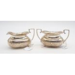 An Edwardian silver sugar bowl and cream jug, the bodies fluted, with twin reeded handles, with