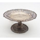 A sivler tazza, with scrolling foliate openwork, the body engraved with a crest, supported by '