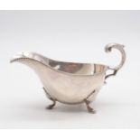 An Edwardian silver sauce boat, with a beaded border, with a flying scroll handle, supported on