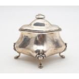 An Edwardian silver sugar box, of bombe form, supported on four paw feet, the body monogrammed, by