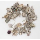 A silver and white metal extensive charm bracelet, to include opening charms, treasure chest, pig,