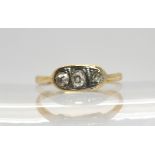 An 18ct gold three stone diamond ring set with two old cuts and a modern brilliant cut, with an