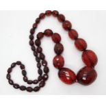 A long string of cherry amber coloured beads, largest bead approx 4cm x 3.2cm, length 76cm, weight