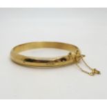 An 18ct gold engraved bangle, inner diameter 6cm, with box clasp and two safety clasps, weight 14gms