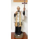 A 20th century ecclesiastical statue of Saint Francis Xavier holding up a crucifix in reverence on