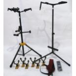 A Hercules tri guitar stand, double guitar stand, music stand and guitar wall hangers together
