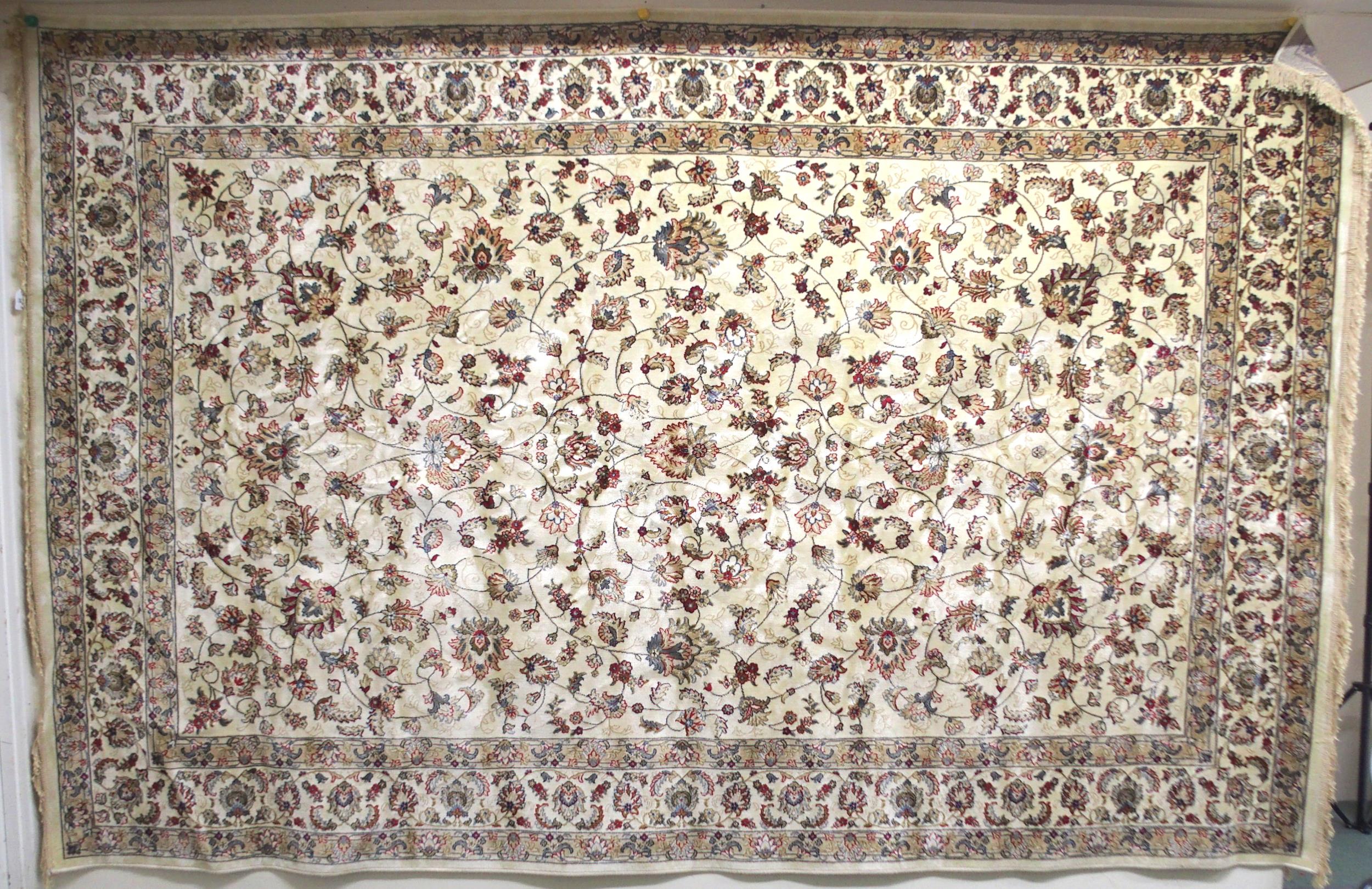 A cream ground machine made Kashmiri rug with all-over floral design and flower head borders,