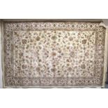 A cream ground machine made Kashmiri rug with all-over floral design and flower head borders,