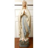 A 20th century ecclesiastical statue of Mary with hands clasped in prayer stood on a bed of roses,