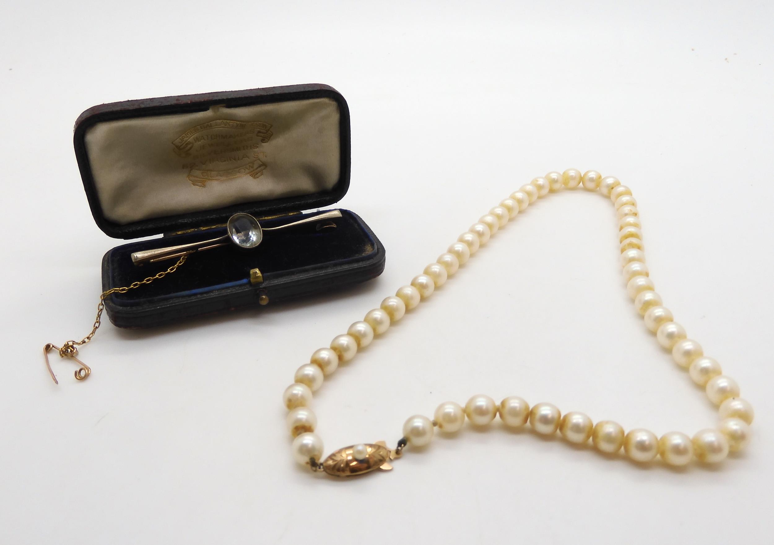 A string of cultured pearls with a 18ct gold pearl set clasp, and a 15ct gold aquamarine brooch,