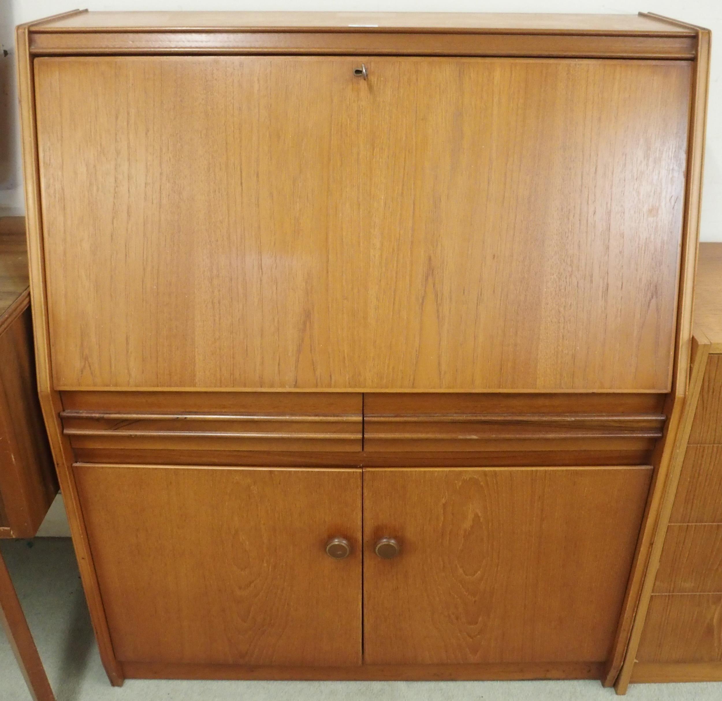 A mid 20th century teak writing bureau with fitted fall front writing compartment over two drawers