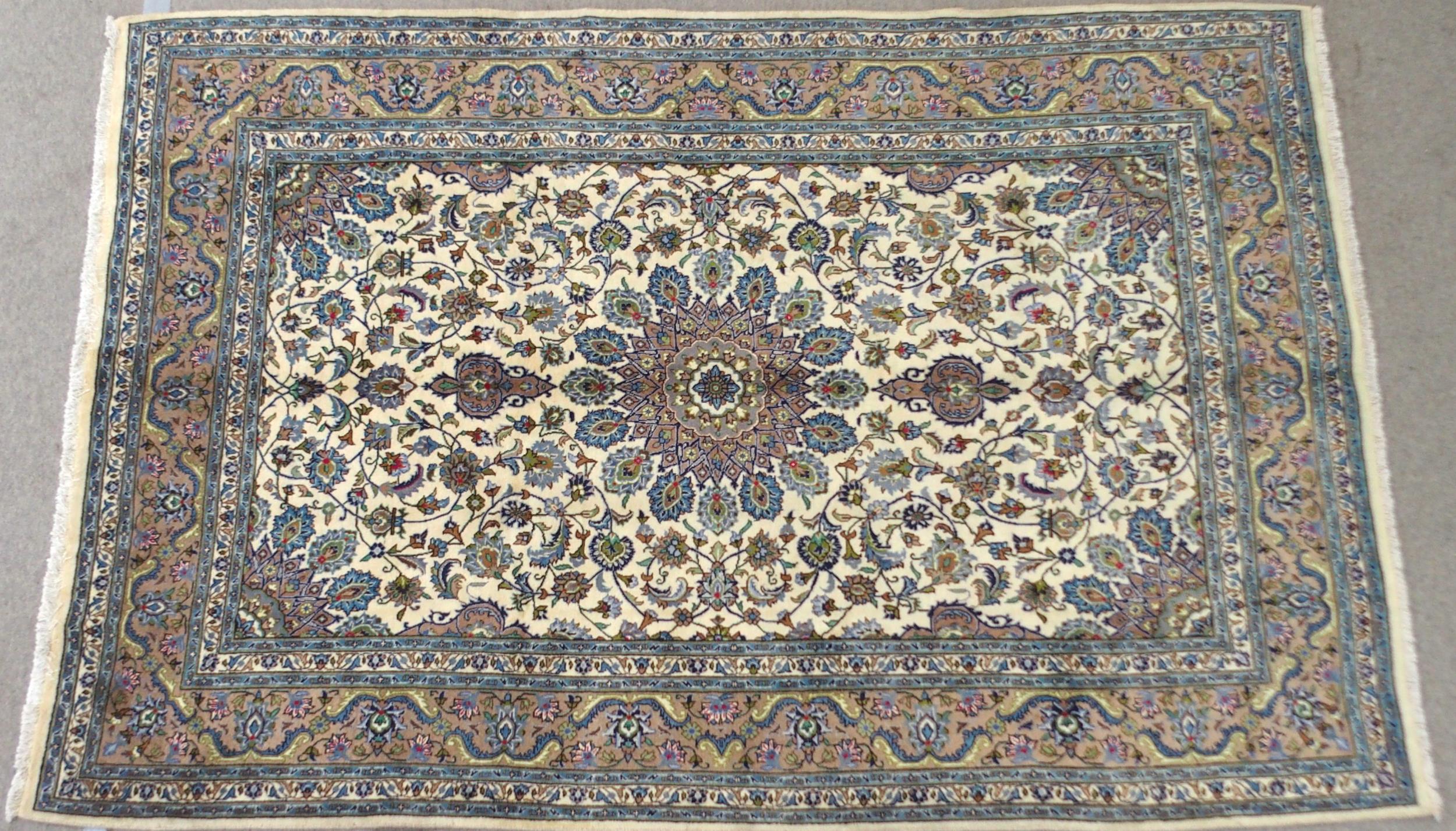 A CREAM GROUND MESHED RUG with multicolour flower head central medallion, matching spandrels and
