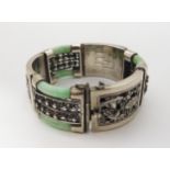 A CHINESE WHITE METAL AND JADE BRACELET with alternate white metal chased foliate panels and