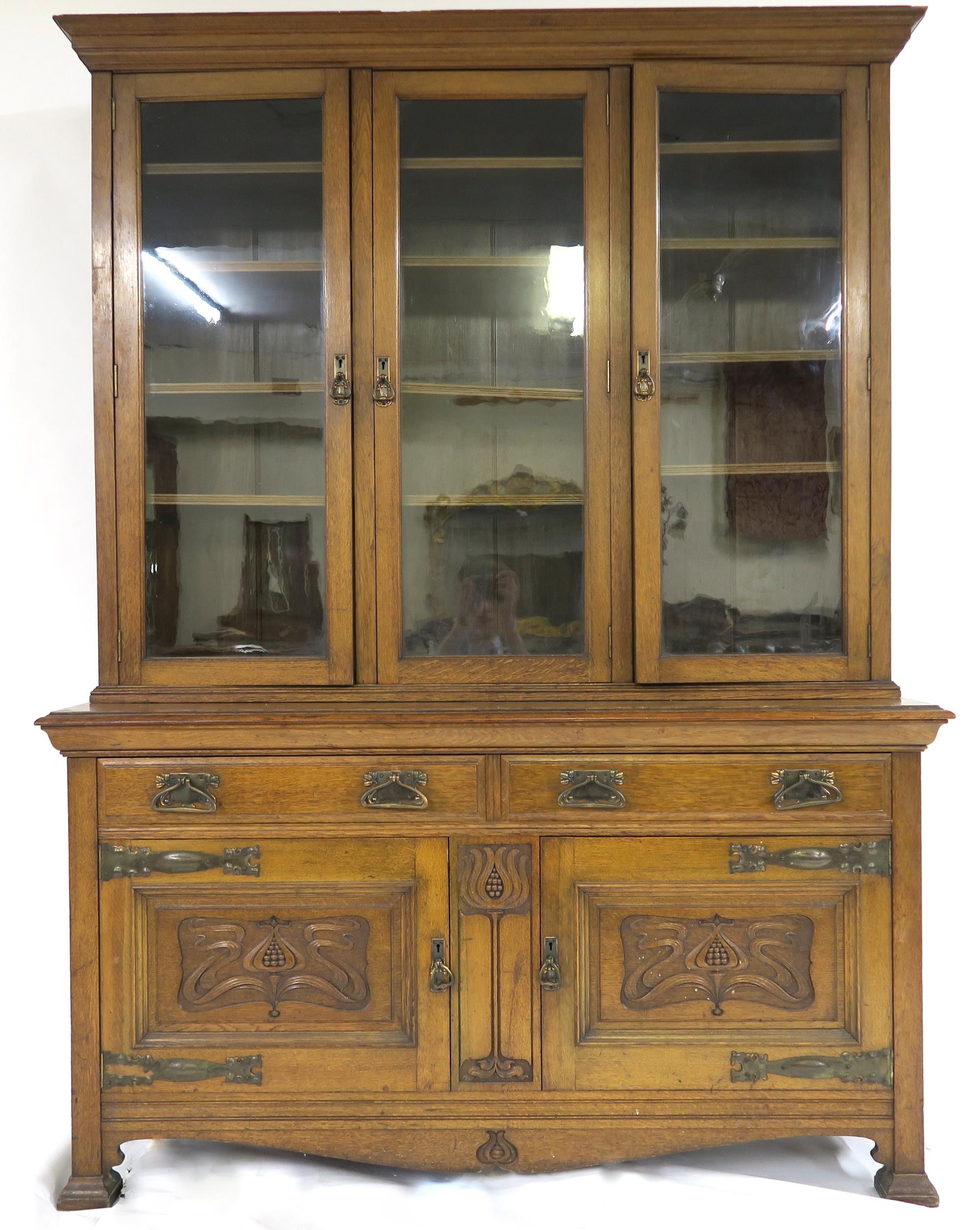 A LATE VICTORIAN OAK ARTS & CRAFTS BOOKCASE with moulded cornice over three glazed doors over two
