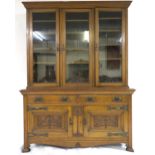 A LATE VICTORIAN OAK ARTS & CRAFTS BOOKCASE with moulded cornice over three glazed doors over two
