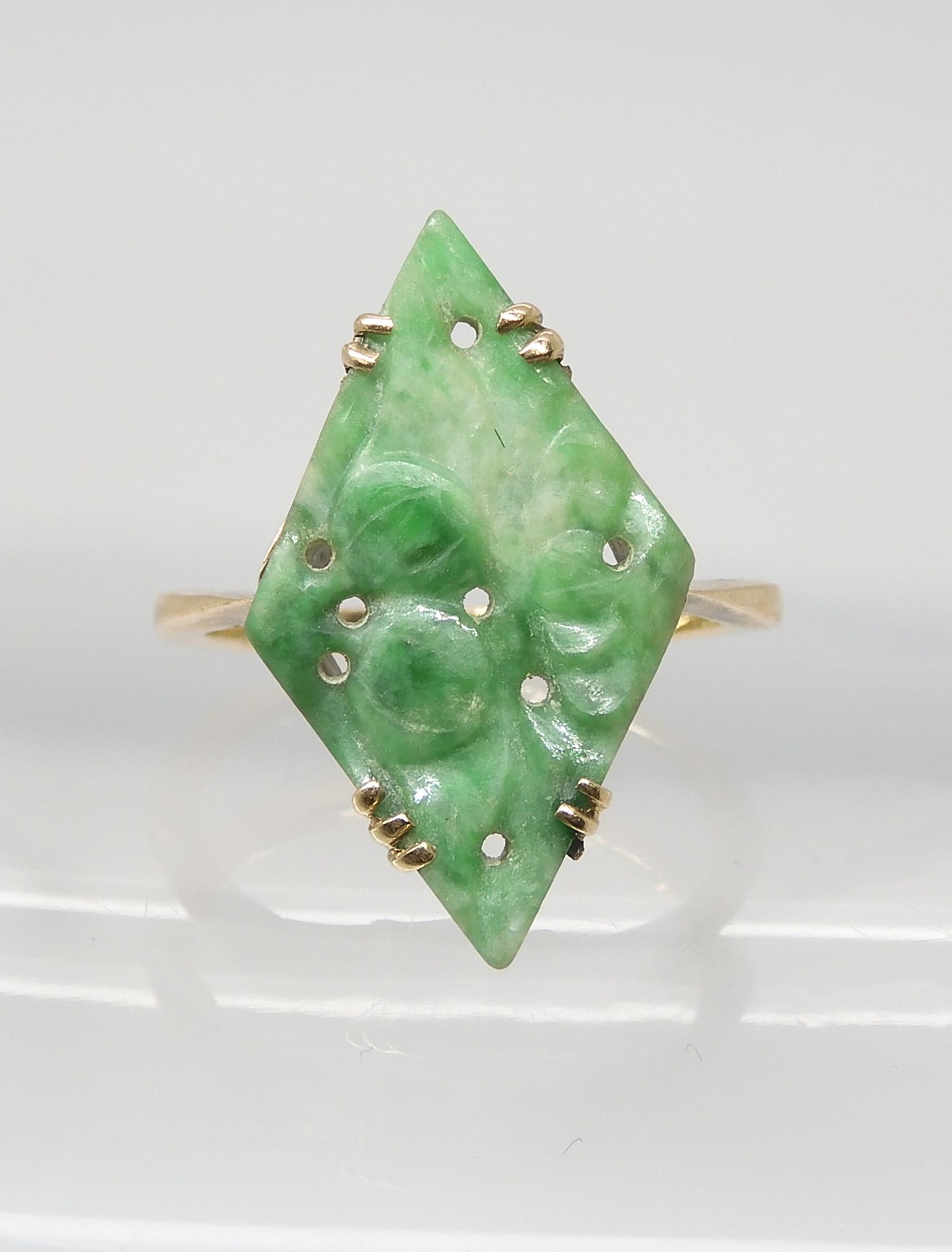 A CHINESE GREEN HARDSTONE RING set with a lozenge shaped plaque, carved with fruit. In a 9ct gold