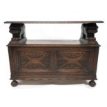 AN EARLY 20TH CENTURY CARVED OAK MONKS BENCH carved hinged top over carved lion arms flanking
