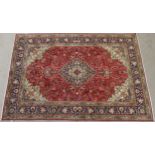 A RED GROUND TABRIZ RUG with dark blue and cream central medallion, matching spandrels and a dark