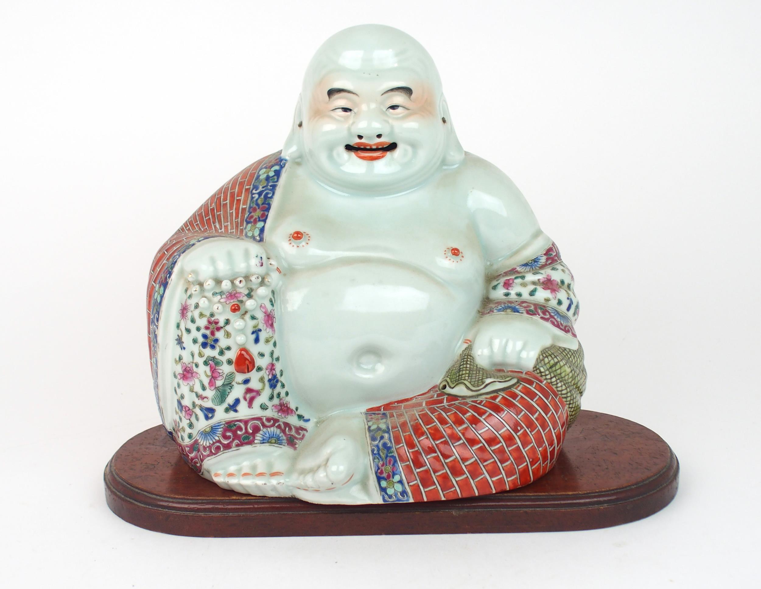 A CHINESE MODEL OF BUDDHA  seated with rosary beads and patterned costume, on a wooden stand,