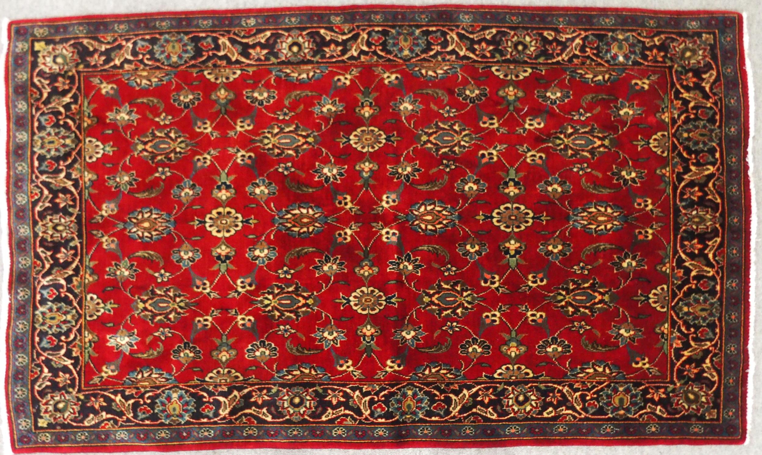 A RED GROUND TABRIZ RUG with all-over floral design and dark blue flower head border, 166cm long x