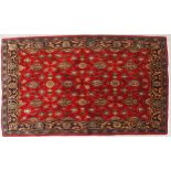 A RED GROUND TABRIZ RUG with all-over floral design and dark blue flower head border, 166cm long x