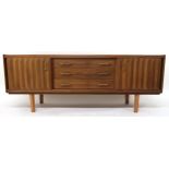 A MID 20TH CENTURY TEAK SIDEBOARD with three long central drawers flanked by cabinet doors with