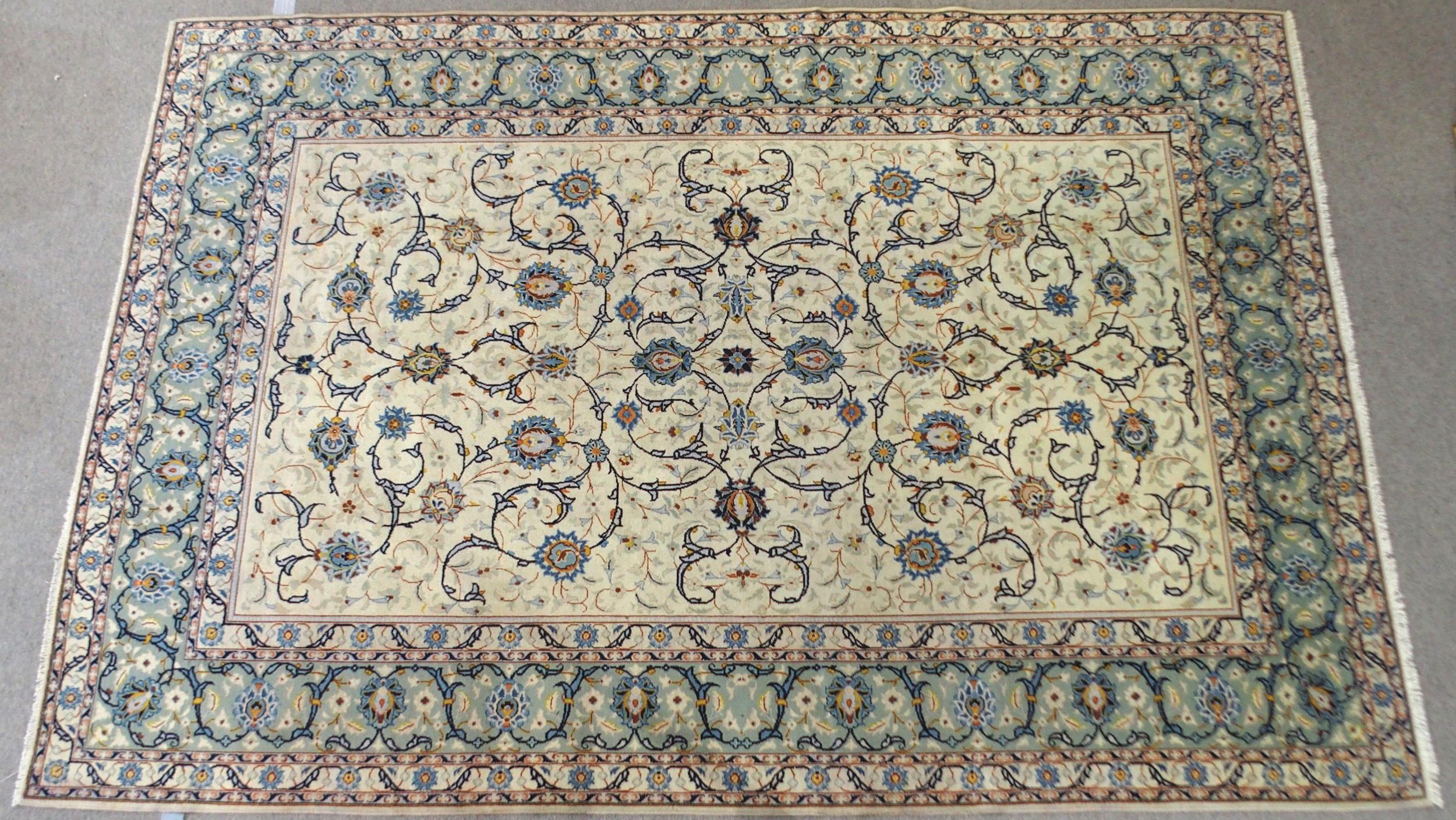A CREAM GROUND KASHAN RUG with all-over floral design and flower head border, 361cm long x 242cm