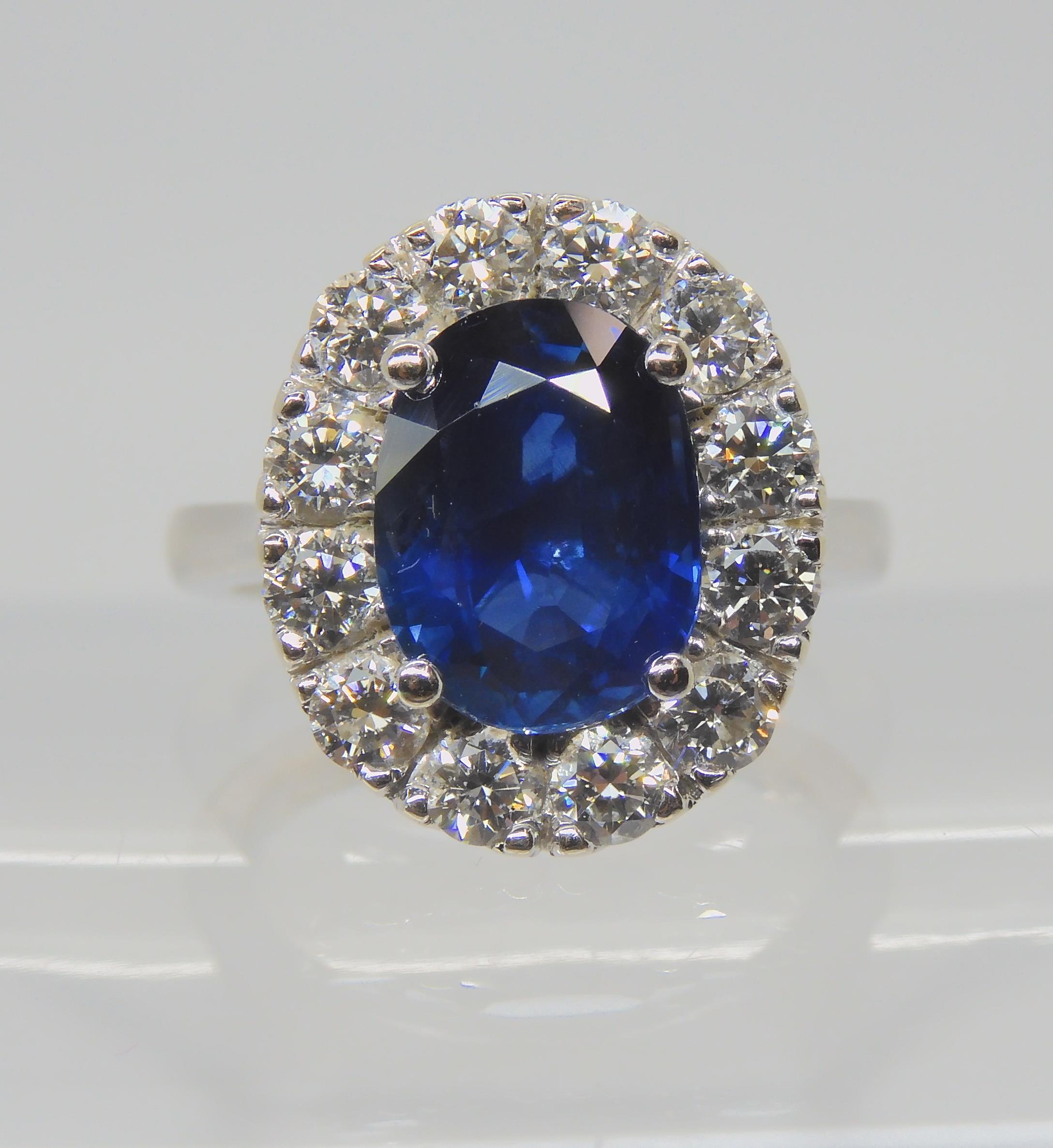 A SAPPHIRE AND DIAMOND CLUSTER RING set throughout in 18ct white gold, set with an oval mixed cut