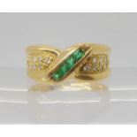 AN EMERALD AND DIAMOND DRESS RING with crossover design with pave set diamond melee and square cut