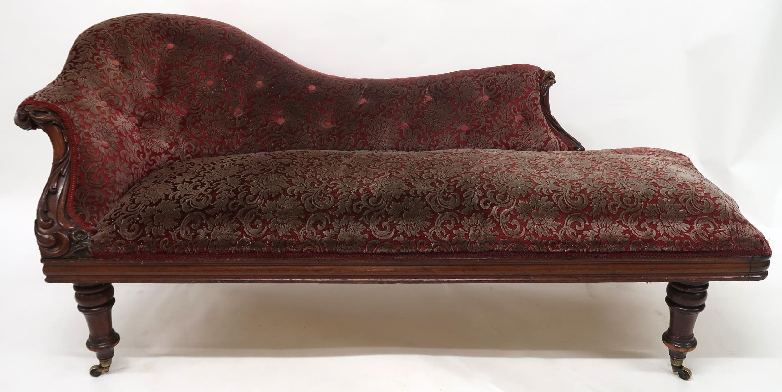 A VICTORIAN MAHOGANY FRAMED CHAISE LONGUE with foliate carvings, buttonback and seat upholstered