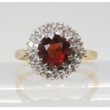 A GARNET AND DIAMOND CLUSTER RING mounted throughout in 18ct gold, the garnet is approx 7mm, and set