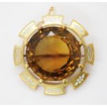 A VICTORIAN LARGE CITRINE BROOCH set in a bright yellow metal and enamelled brooch mount, the